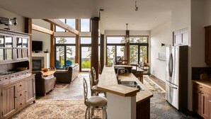 A spacious kitchen with a central island, wooden cabinets, and large windows offering views of the outdoors. - Ocean View Property - Black Rock Ridge (Ucluelet)