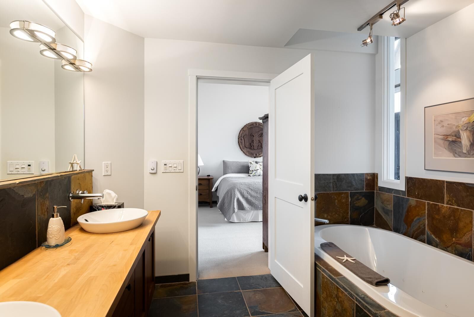 Une salle de bain moderne avec un meuble-lavabo en bois, un grand miroir et une baignoire.