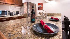 A modern kitchen with granite countertops, stainless steel appliances, and a dining area set with plates and cutlery. - Multnomah Gem - Beautiful, pampering, mins to downtown Portland (Portland)