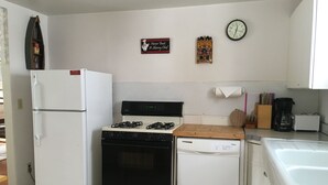 A compact kitchen with a refrigerator, stove, dishwasher, and a clock on the wall. - All You Need Is Personal Items And Food. (Encampment)