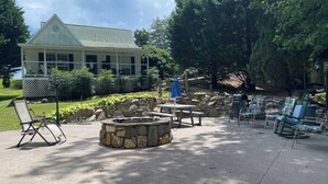 Un espace extérieur aménagé avec un foyer en pierre, une table de pique-nique et des chaises longues.