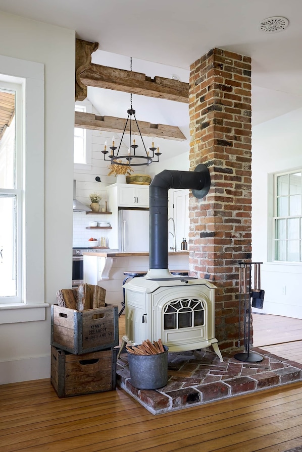 A rustic kitchen with a brick chimney, wooden beams, and a vintage stove.