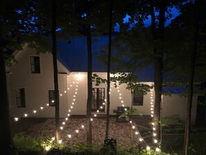 A house with a herringbone-patterned patio, string lights, and a door leading to the interior.
