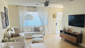 A modern living room with a white sofa, a round coffee table, a TV, and a wooden entertainment unit. - Waterfront Luxury- 3 Plus Bedrooms (Clearlake Oaks)