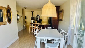 A dining area with a large table and white chairs, a hanging light fixture, and ornate mirrors on the walls. - Waterfront Luxury- 3 Plus Bedrooms (Clearlake Oaks)