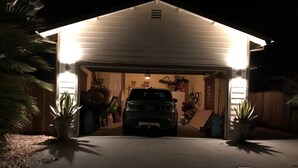 A garage with a vehicle parked inside, surrounded by potted plants and various items. - Waterfront Luxury- 3 Plus Bedrooms (Clearlake Oaks)