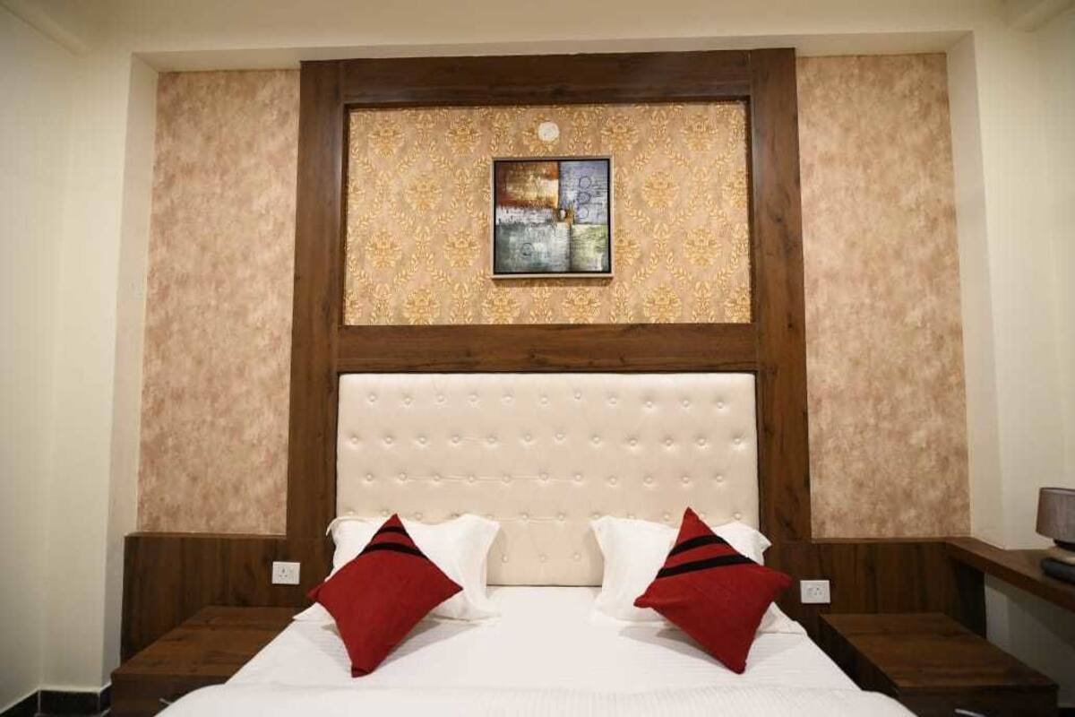 Een hotelkamer met een groot bed, een houten hoofdeinde en een decoratief wandpaneel erboven.