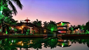A resort with a pool reflecting the buildings and palm trees. - Scorpio Clubs & Resorts (Bakshi Ka Talab)