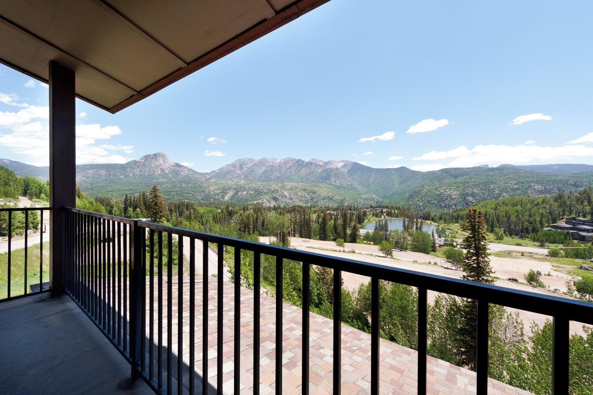 A balcony with a view of mountains, a lake, and a forest.