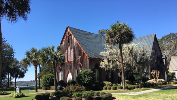 A large wooden building with a steep roof, surrounded by well-maintained lawns and trees. - A Charming Carriage House Apartment in Stock Farm in Old Town Bluffton (Bluffton)