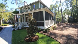 A two-story house with a porch, a screened porch, and a small front yard with a tree. - A Charming Carriage House Apartment in Stock Farm in Old Town Bluffton (Bluffton)