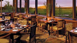 A restaurant with multiple tables set for dining, large windows offering a view of a green landscape, and a patterned carpet. - Sunriver Gem - SHARC Pass |  Hot Tub |  Fireplace (Bend)