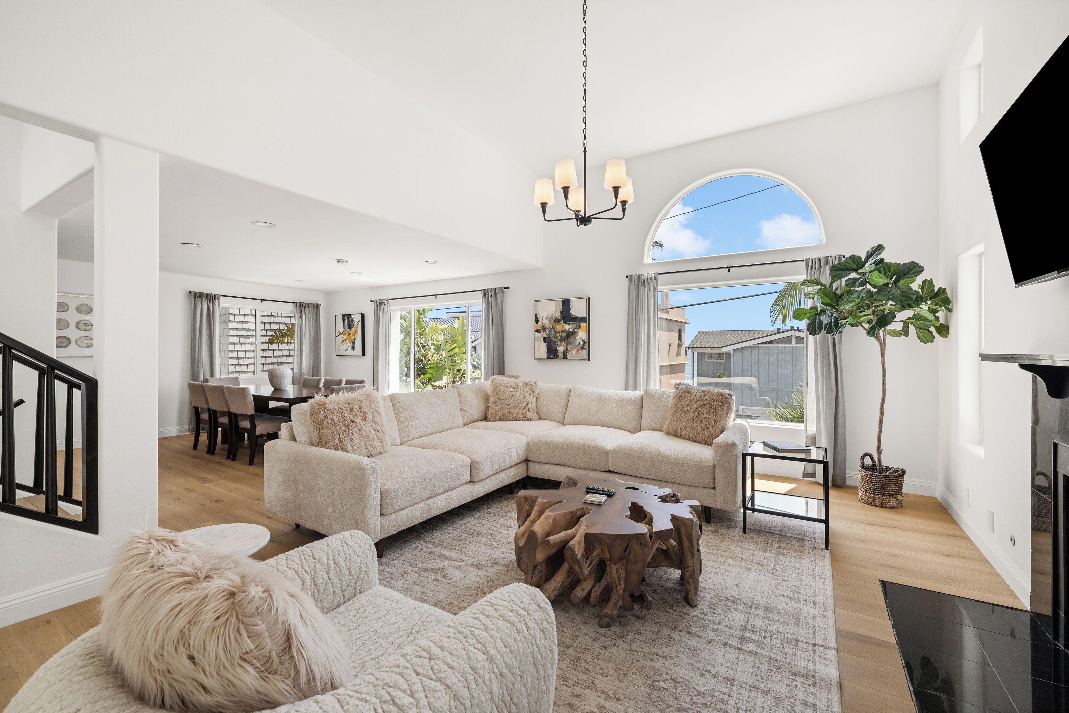 A spacious living room with a large sectional sofa, a coffee table, and a fireplace. There is a dining area with a table and chairs visible in the background.