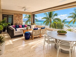 A balcony with a view of the ocean, a sofa set, and a dining table.