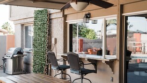 An outdoor patio with a grill, two chairs, and a table.