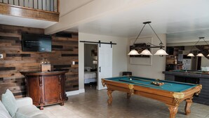 A pool table in a room with a wooden wall and a white door.