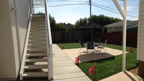 A backyard with a patio, a covered seating area, and a staircase leading to an upper level.
