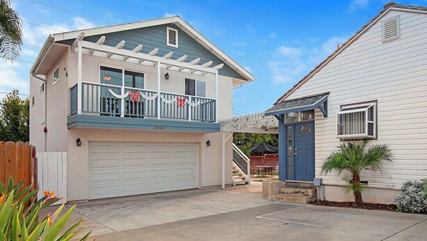A two-story house with a garage, a covered porch, and a small outdoor seating area.