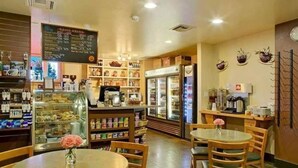 Una cafetería con una pizarra de menú, vitrina refrigerada y zona de mesas.