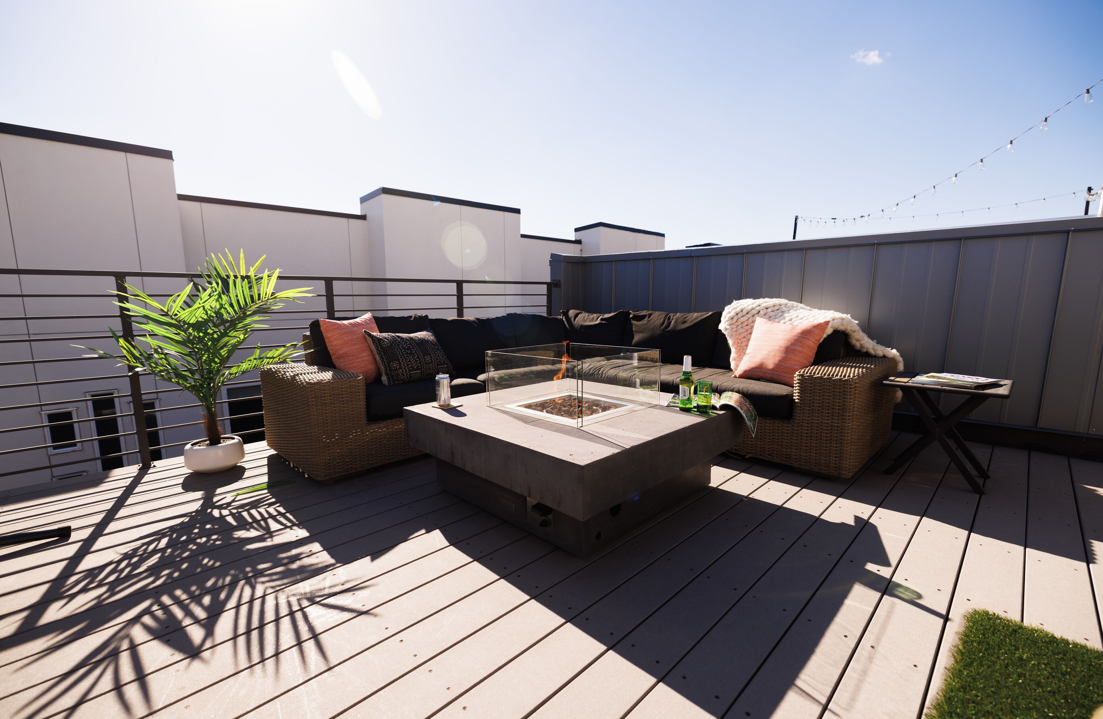 A rooftop patio with a concrete fire pit, wicker furniture, and a potted plant.