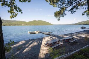 A lakeside picnic area with benches and a dock extending into the water.