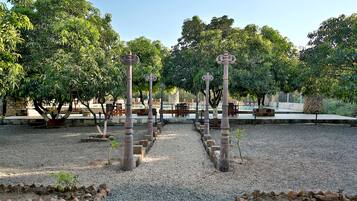 Un jardin agrémenté de piliers en pierre, de chemins de gravier et d’arbres.