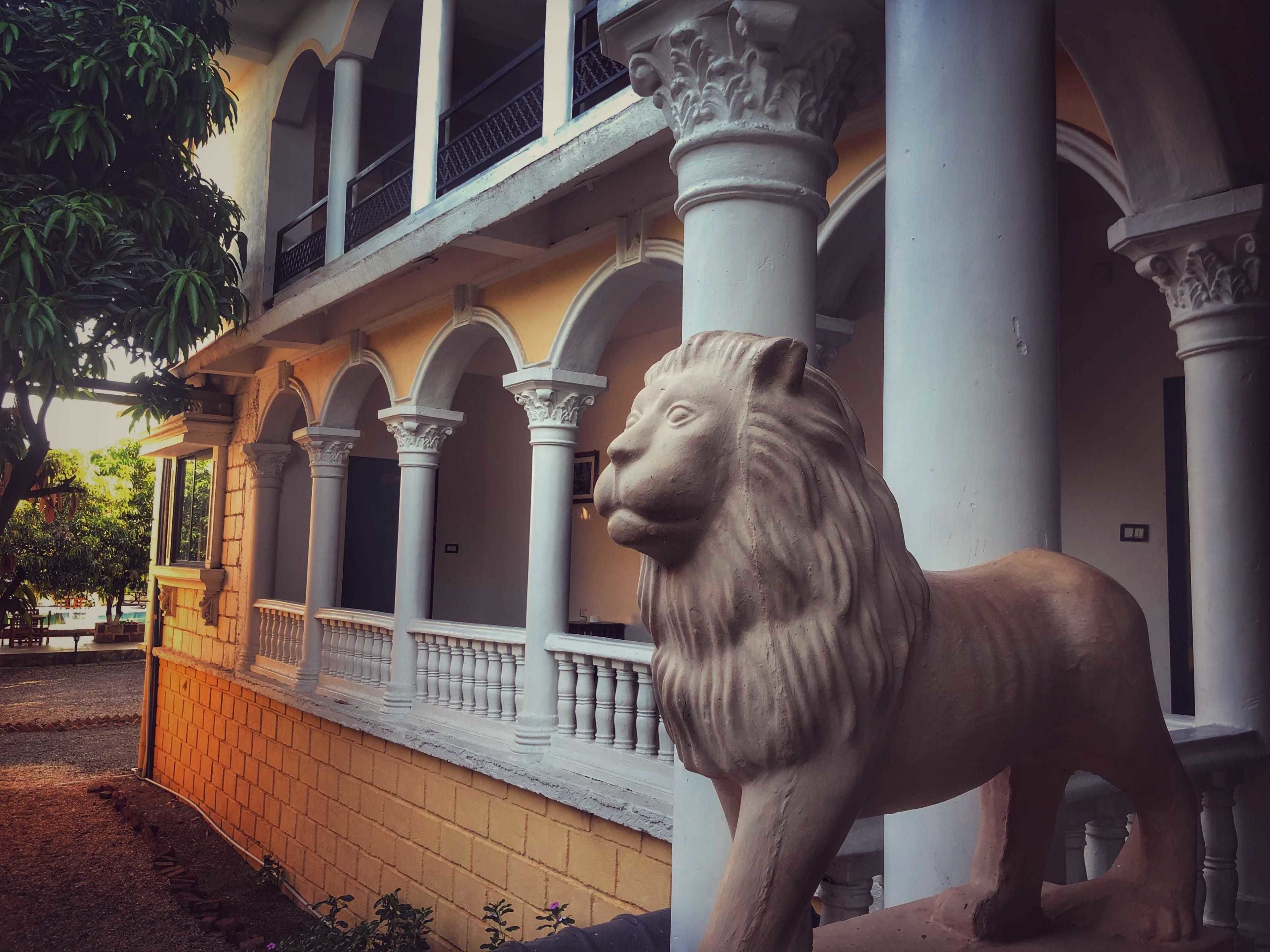Un edificio con una estatua de león, columnas y un paseo cubierto.