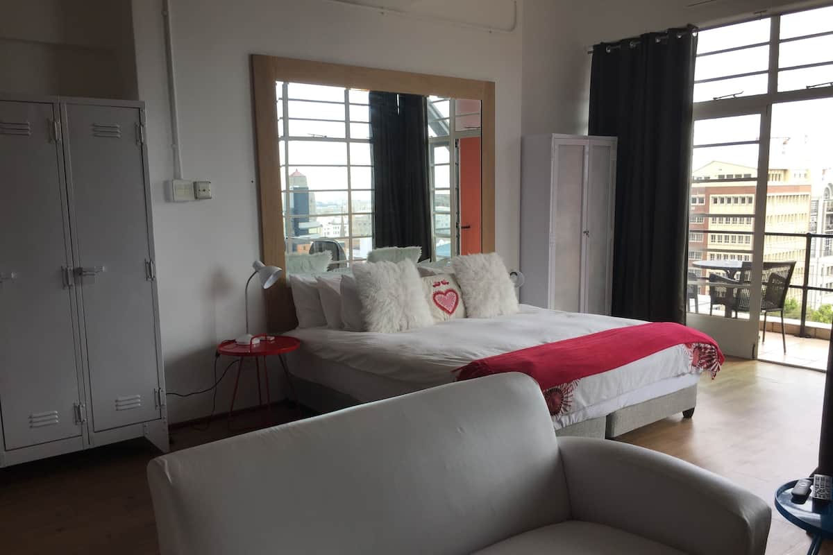 A hotel room with a bed, a chair, a desk, and a wardrobe.