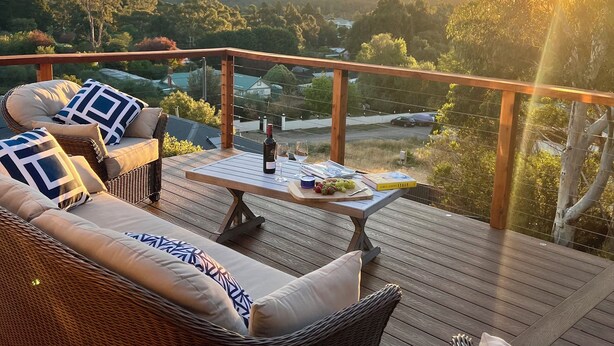Terraza con mobiliario de mimbre y una mesa preparada para una comida, con vistas a un paisaje pintoresco.