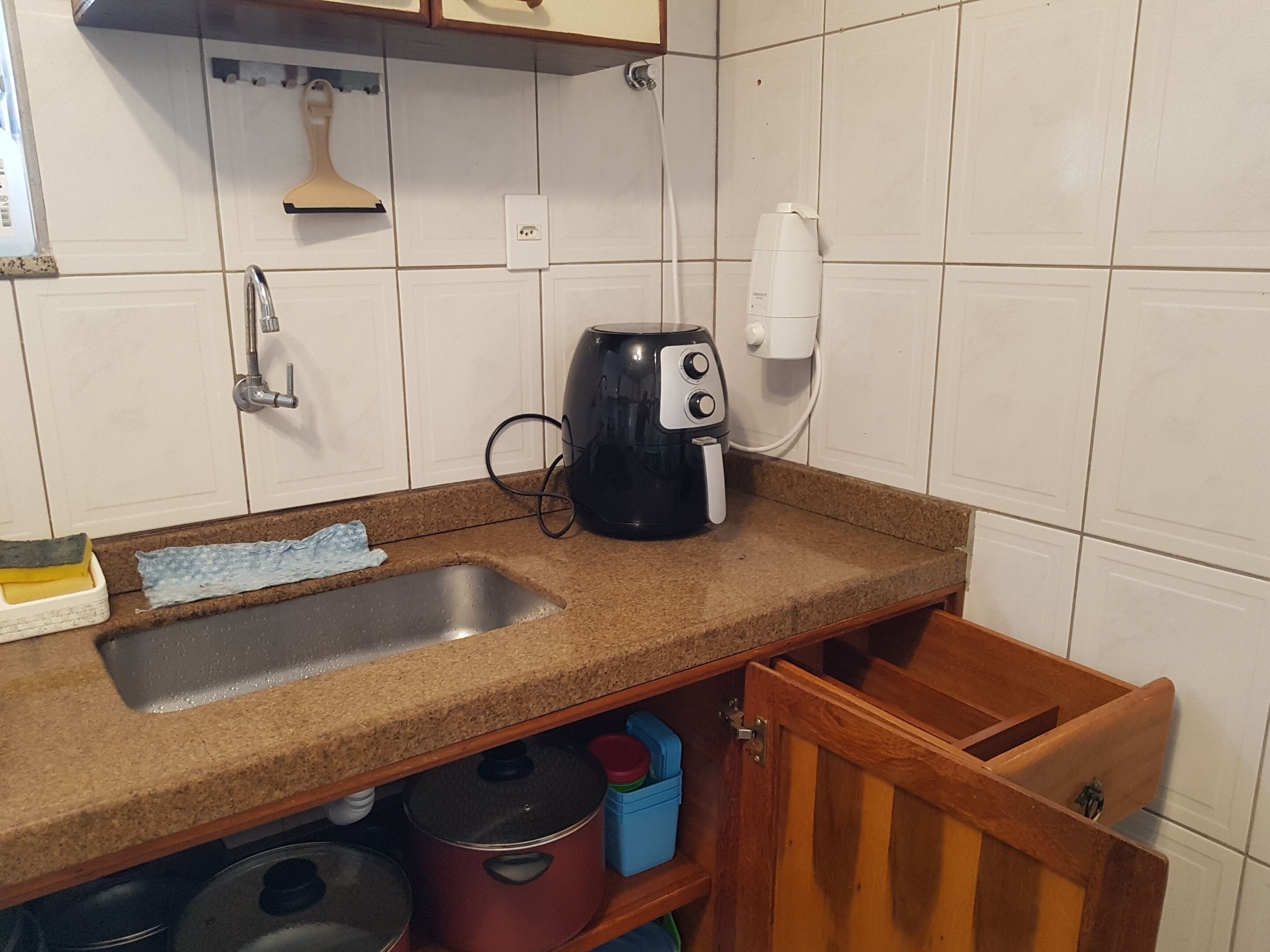A kitchen with a sink, a coffee maker, and cabinets.