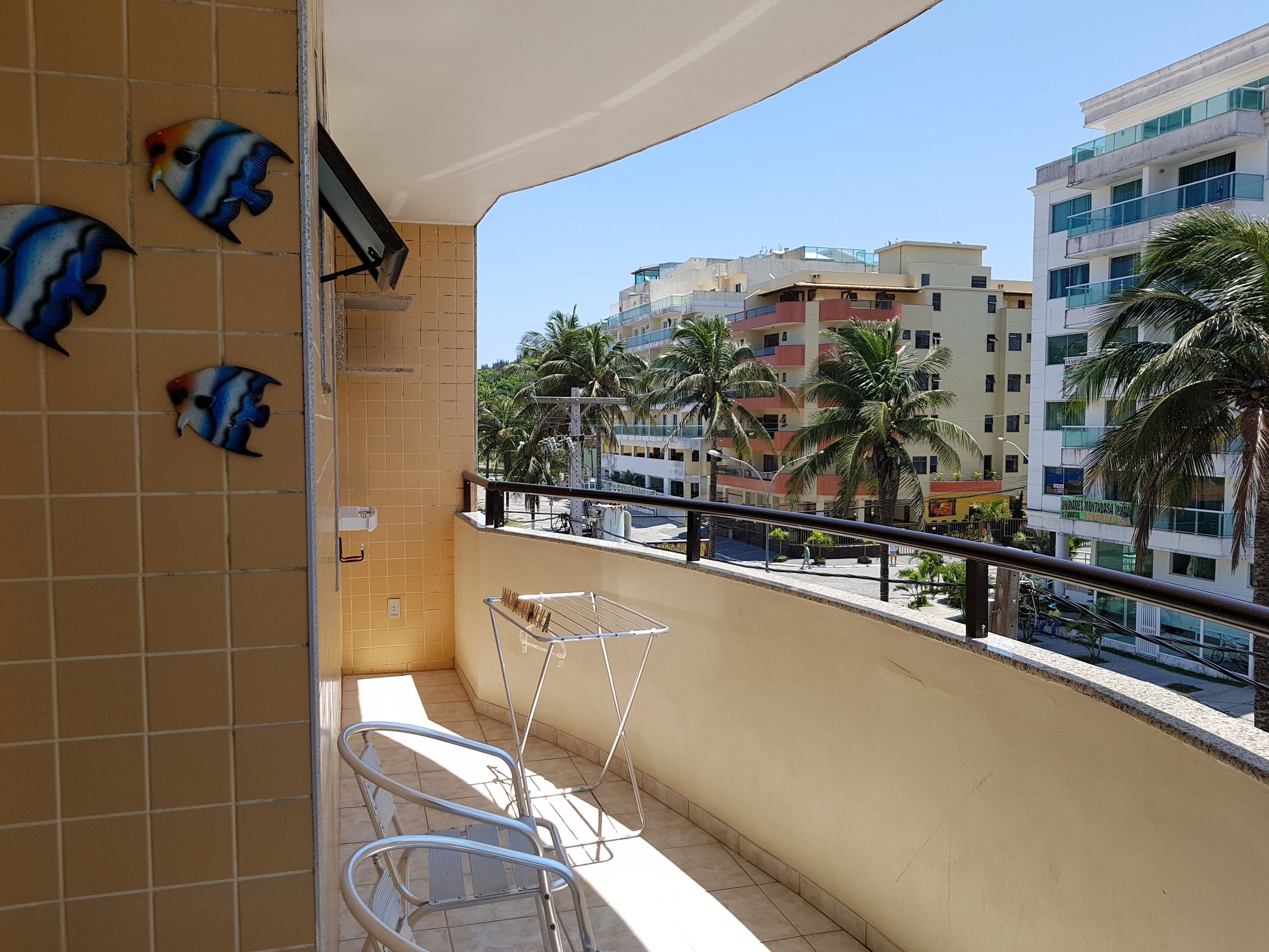 A balcony with tiled walls, a metal chair, a small table, and decorative fish.