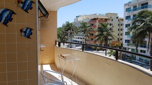 En balkon med fliserede vægge, en metalstol, et lille bord og dekorative fisk.