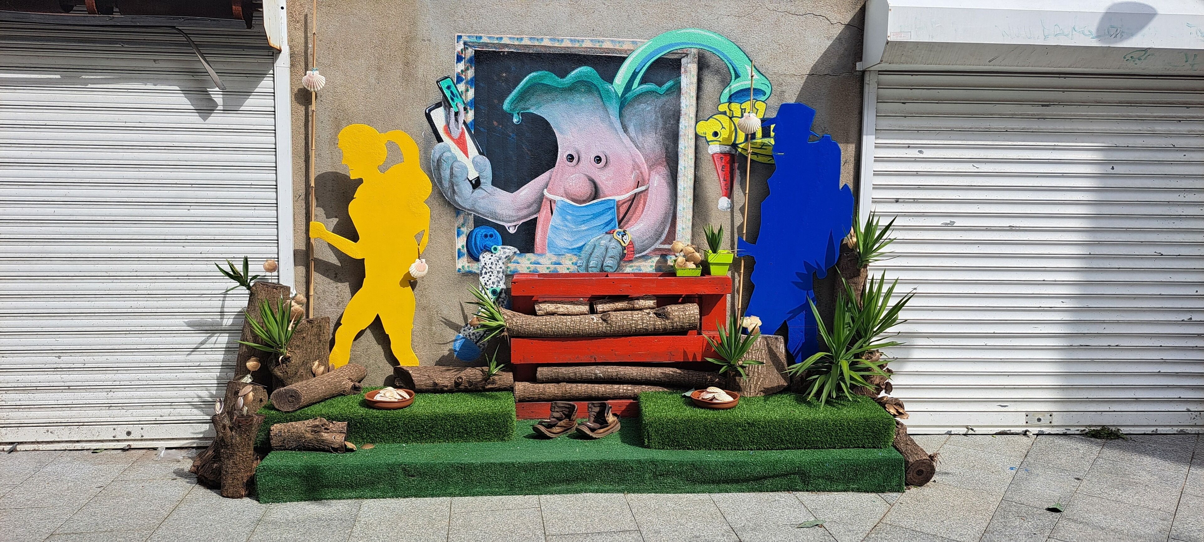 A colorful outdoor display with a cartoon elephant, a yellow figure, and a red bench.