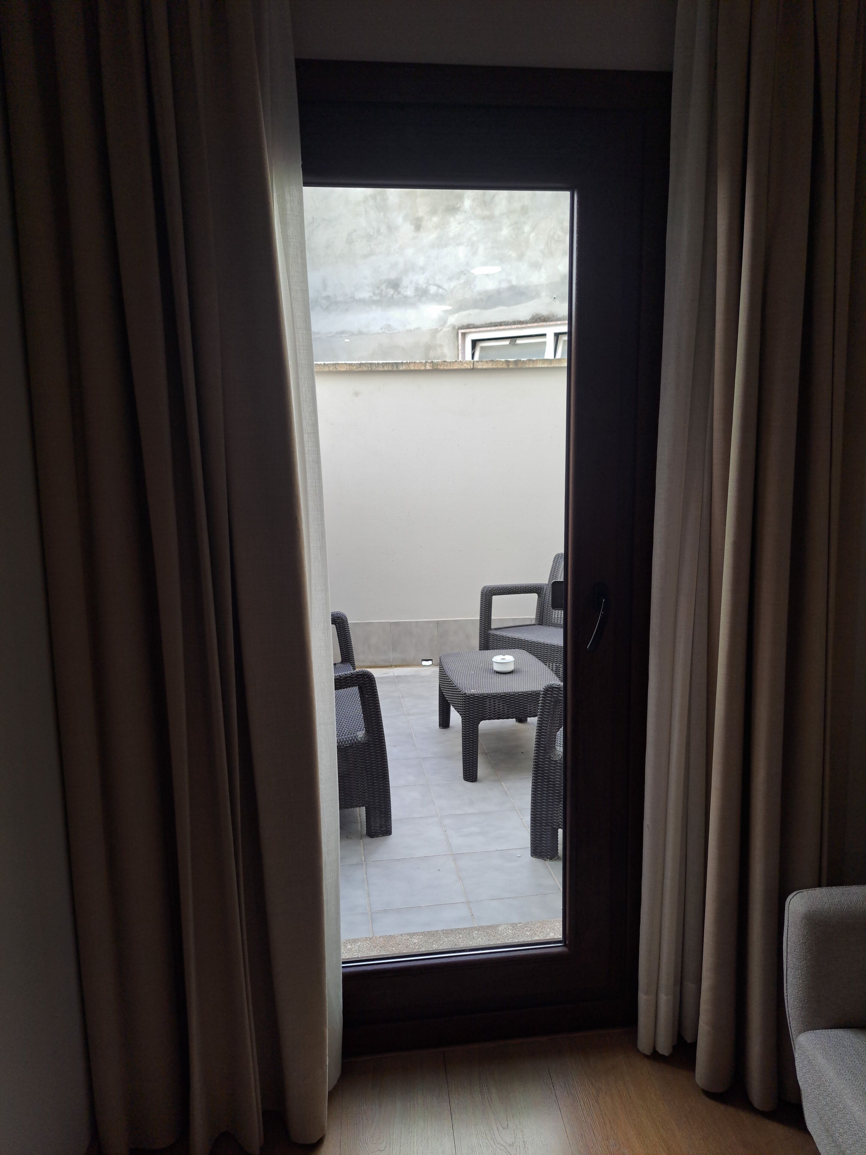 A room with a sliding glass door leading to an outdoor patio area with wicker furniture and a table.