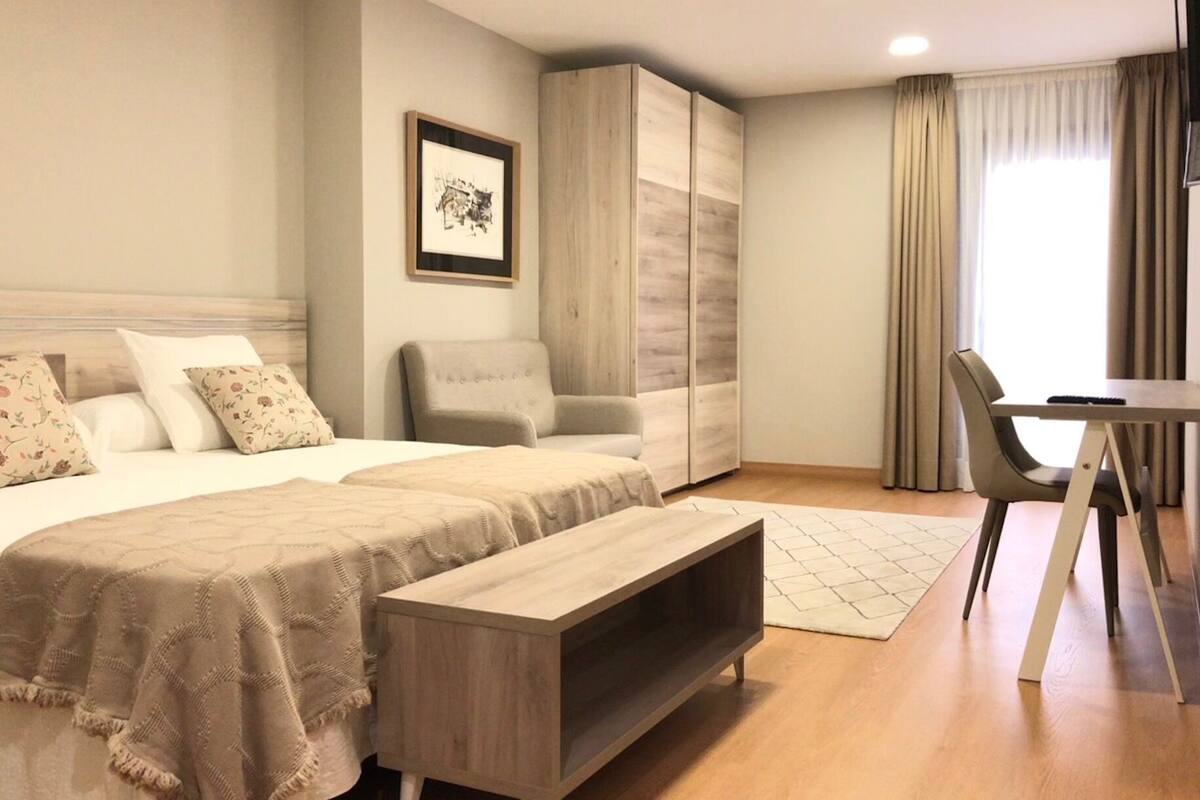Una habitación de hotel moderna con cama, una silla, un escritorio y un armario.