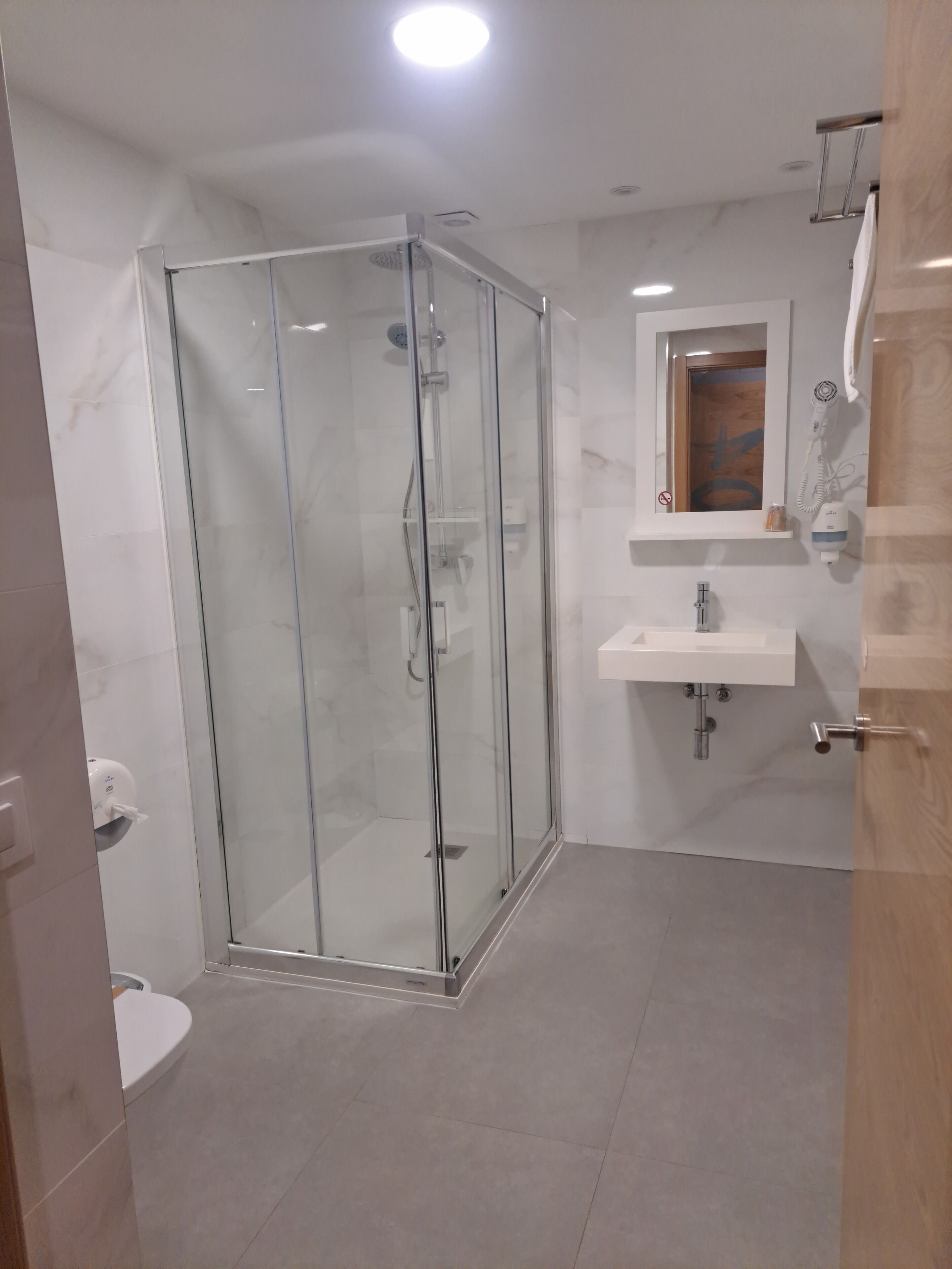 A modern bathroom with a glass-enclosed shower, a white sink, and a mirror above the sink.