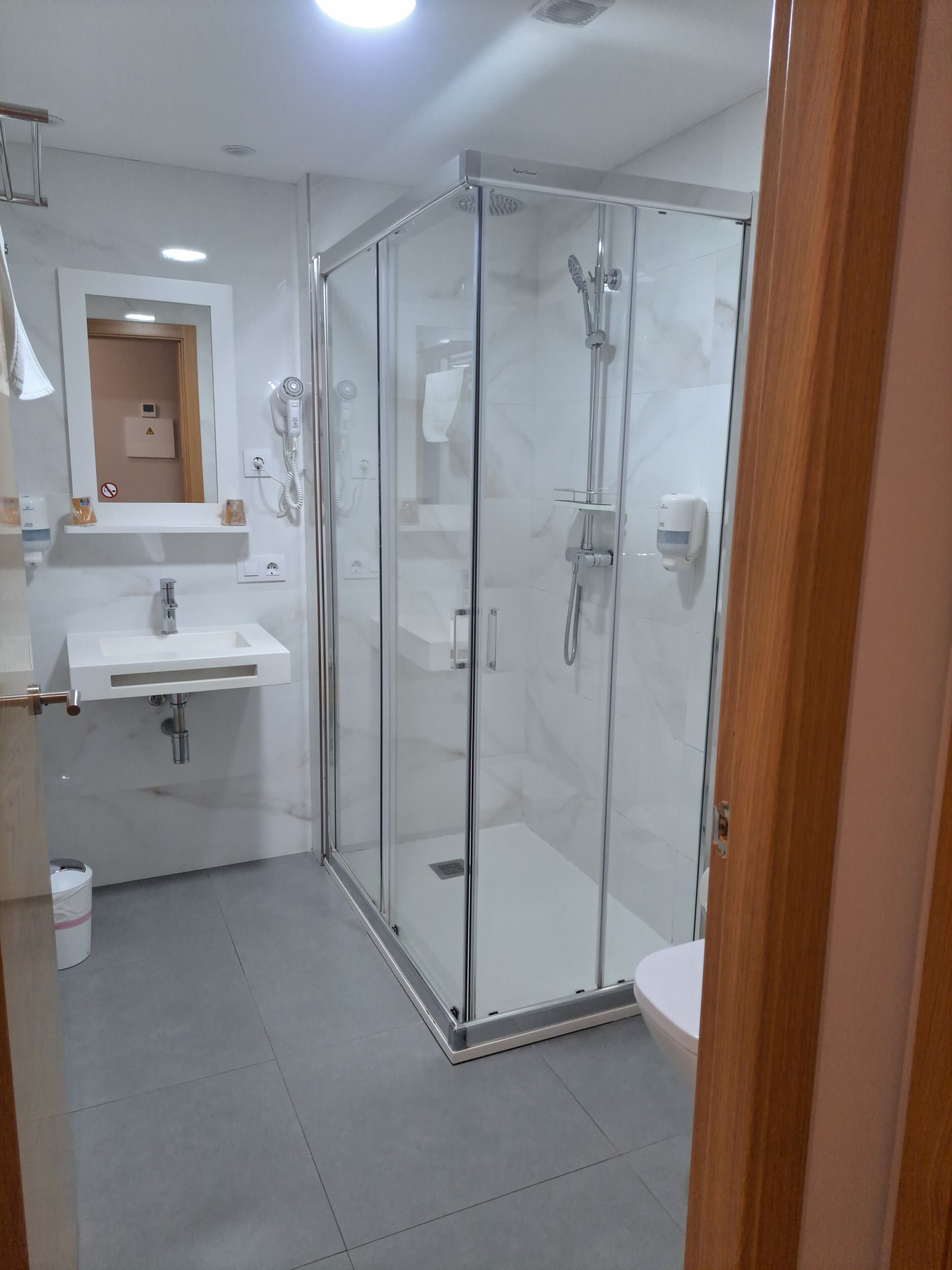 A modern bathroom with a glass-enclosed shower, a white sink, and a mirror above the sink.