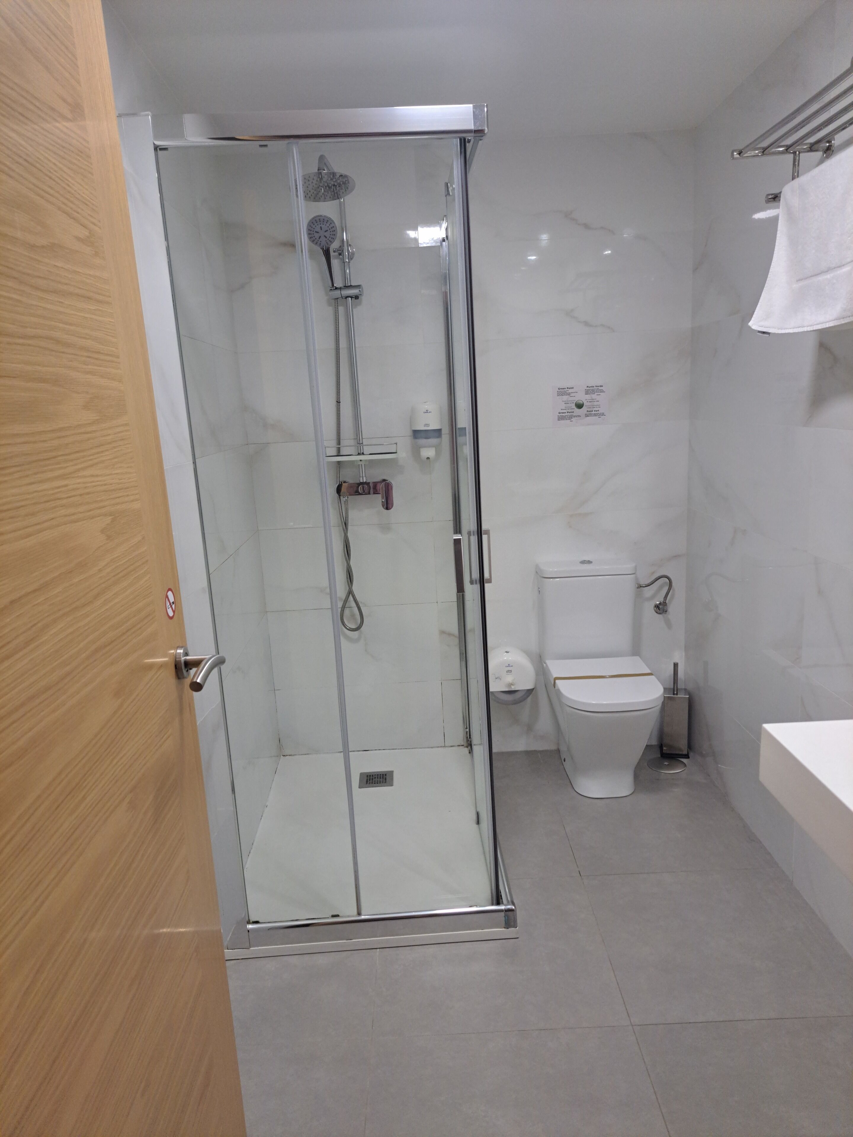 A modern bathroom with a glass-enclosed shower, a toilet, and a sink.