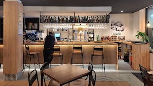 Een moderne bar met een houten toonbank, barstoelen en een scherm.