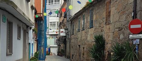A narrow street with stone buildings, a blue construction crane, and a no-entry sign.