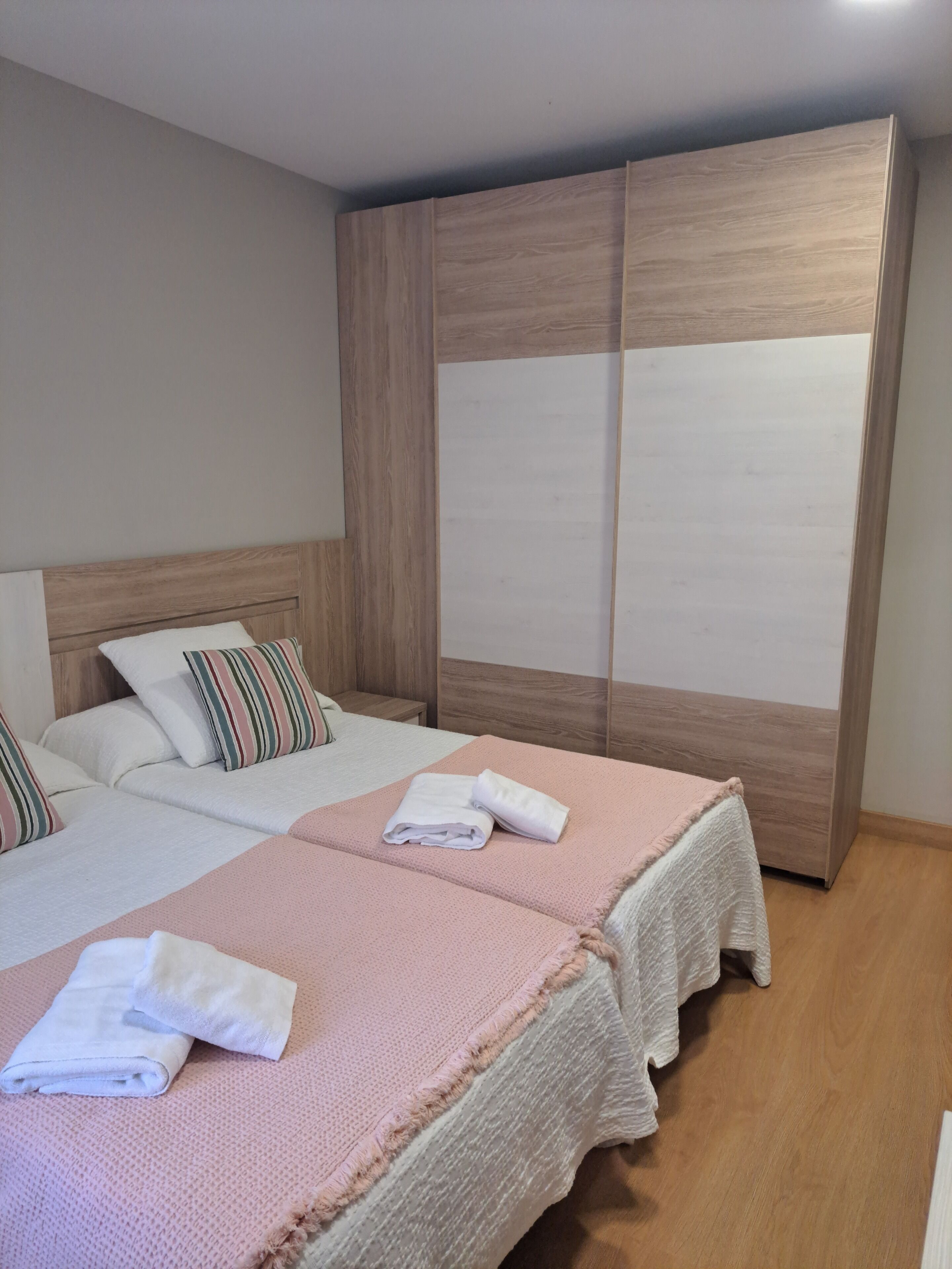 Una habitación de hotel con dos camas, un armario de madera y una mesita de noche.
