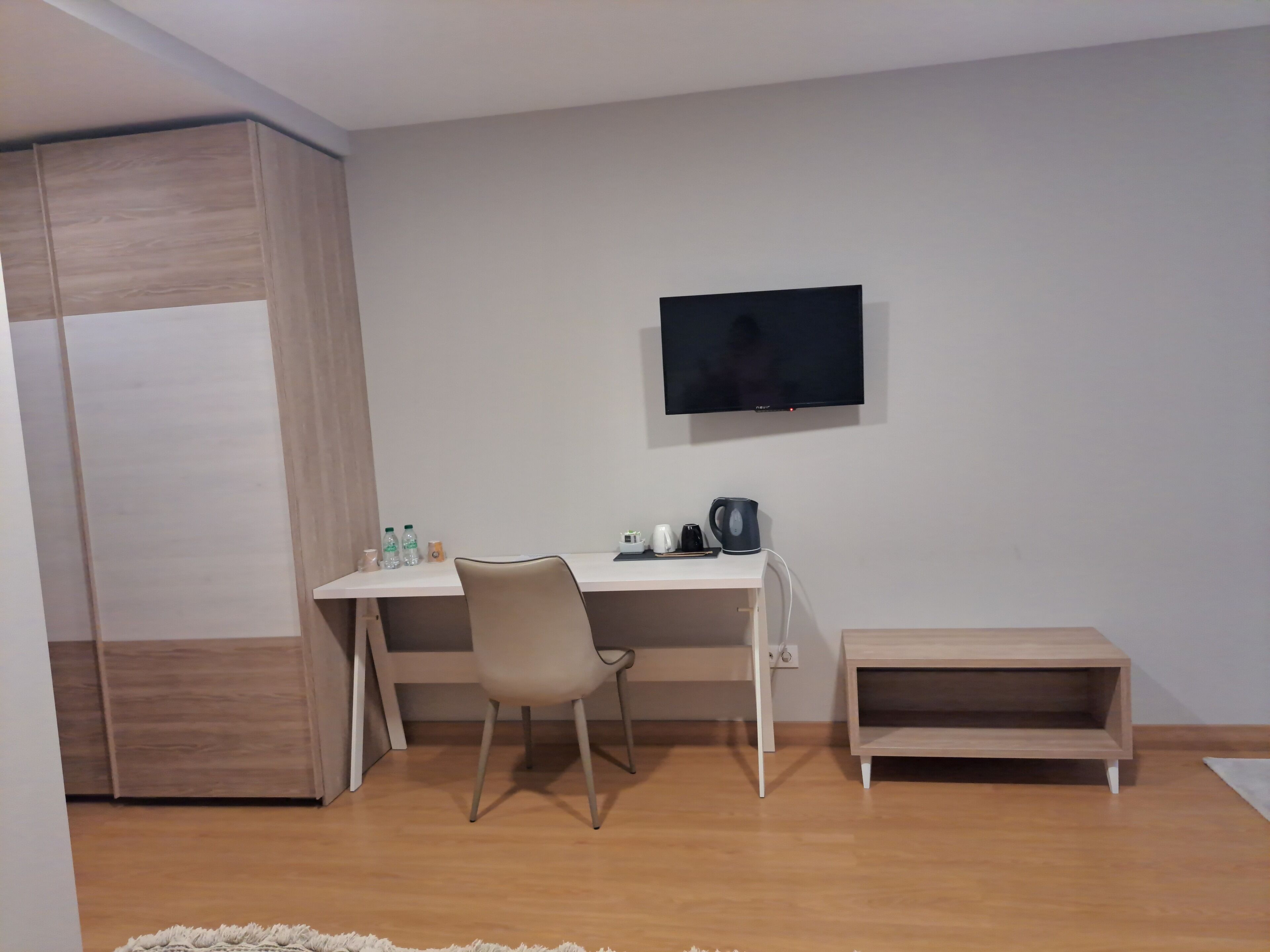 Une pièce comprenant un bureau, une chaise, un téléviseur et une petite étagère.