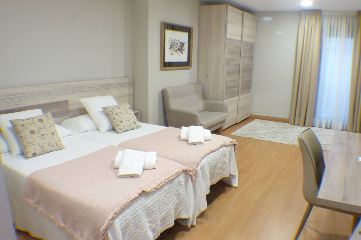 Habitación de hotel con dos camas, un sofá, un escritorio y una silla.