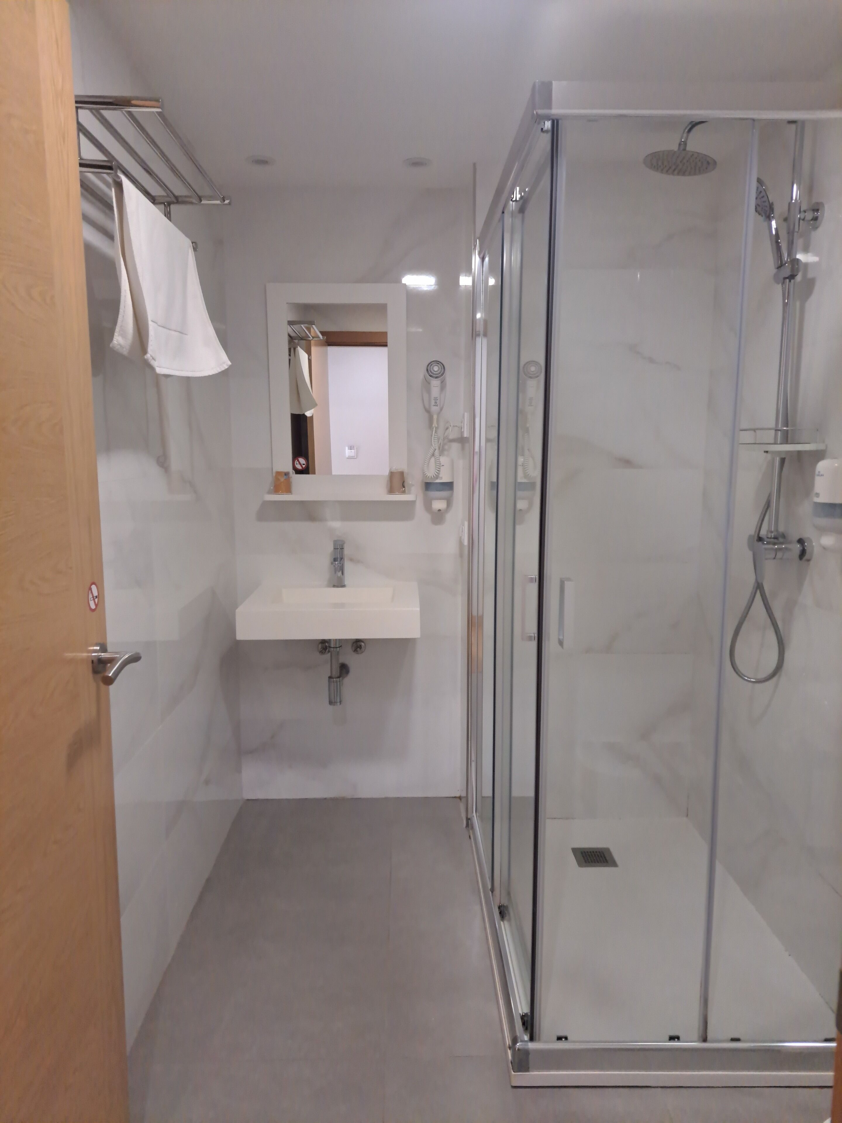 A modern bathroom with a glass-enclosed shower, a sink, and a mirror.