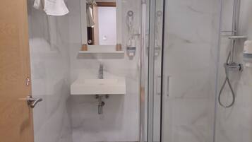 A modern bathroom with a glass-enclosed shower, a sink, and a mirror.