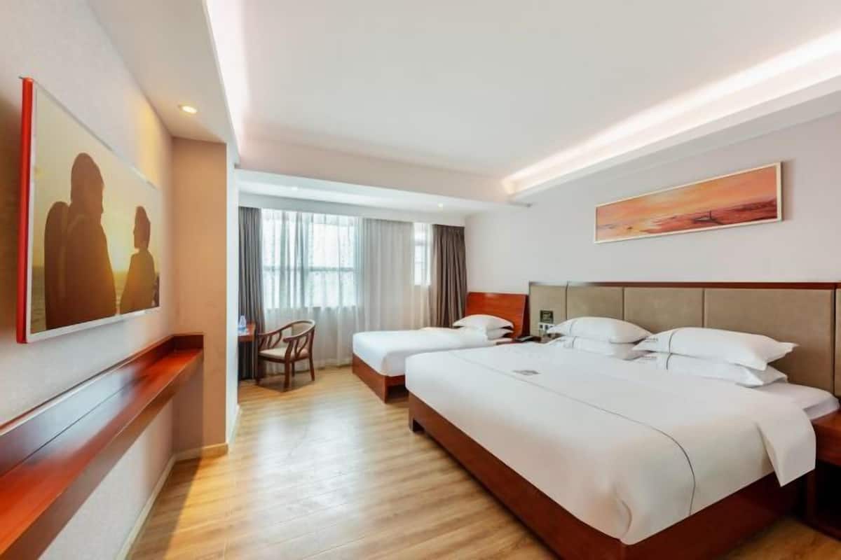 Habitación de hotel con una cama grande, un escritorio y una silla. Hay un cuadro en la pared y una ventana con cortinas.