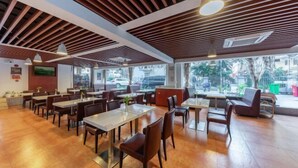 A spacious restaurant with wooden flooring, modern ceiling design, and large windows offering a view of the outside. - King Lycra Hotel(Shenzhen International Convention and Exhibition Center store) (Shenzhen)