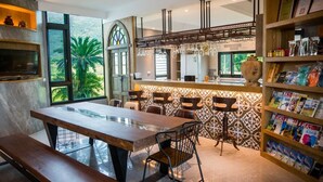 A modern kitchen with a large island, bar stools, and a bookshelf filled with magazines. - The Dawn B&B (Ji'an)