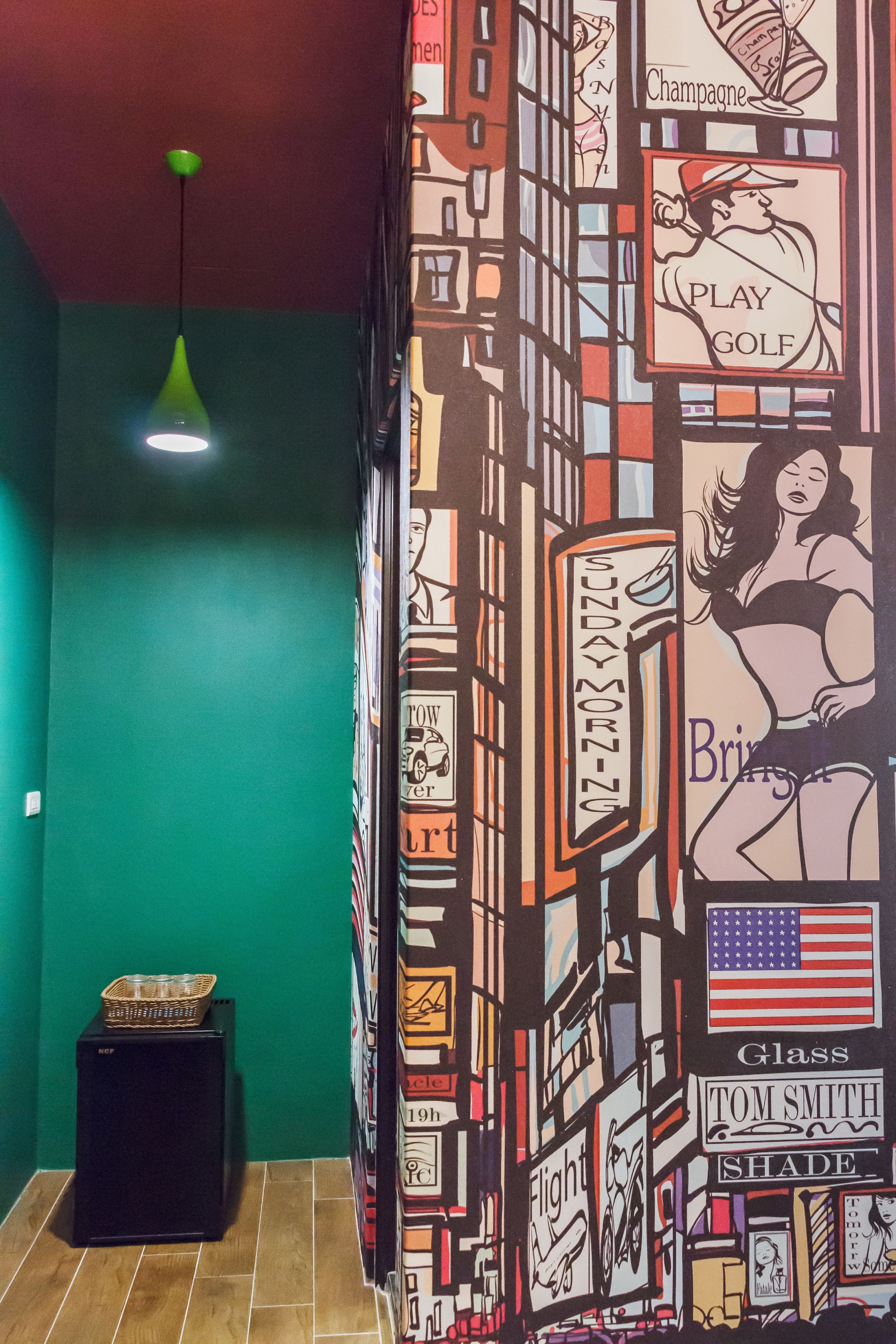 A room with a green wall, a black cabinet, and a patterned wall with various signs and illustrations.