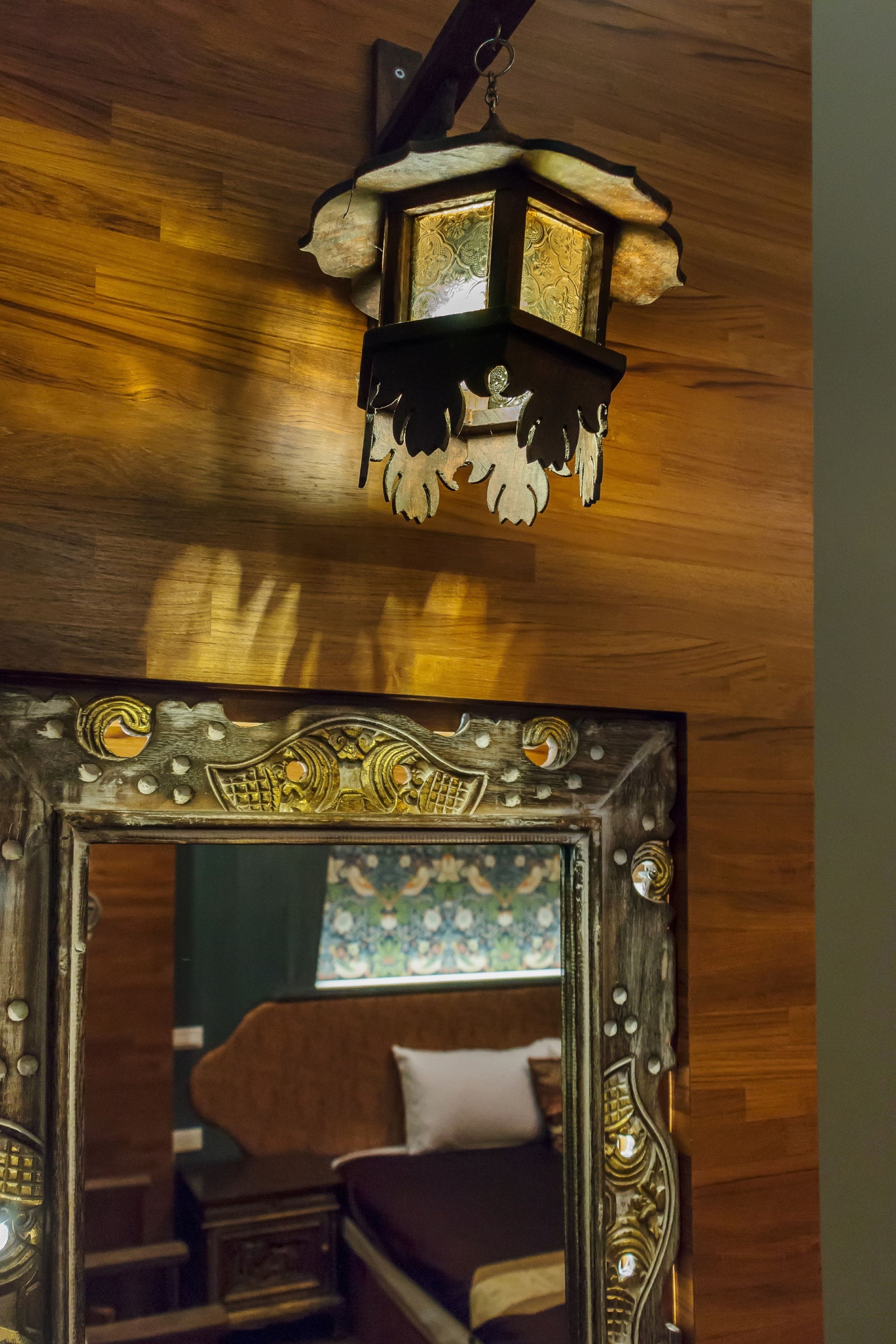 Teto de madeira com um candeeiro pendente e um espelho com detalhes ornamentados.